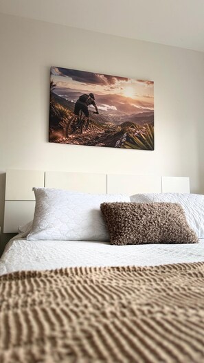 Ein Schlafzimmer mit einem Bett, Kissen und einem Wandbild einer Berglandschaft.