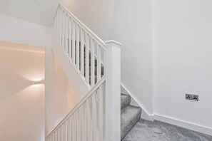 Eine weiße Treppe mit Handlauf und Teppichstufen.
