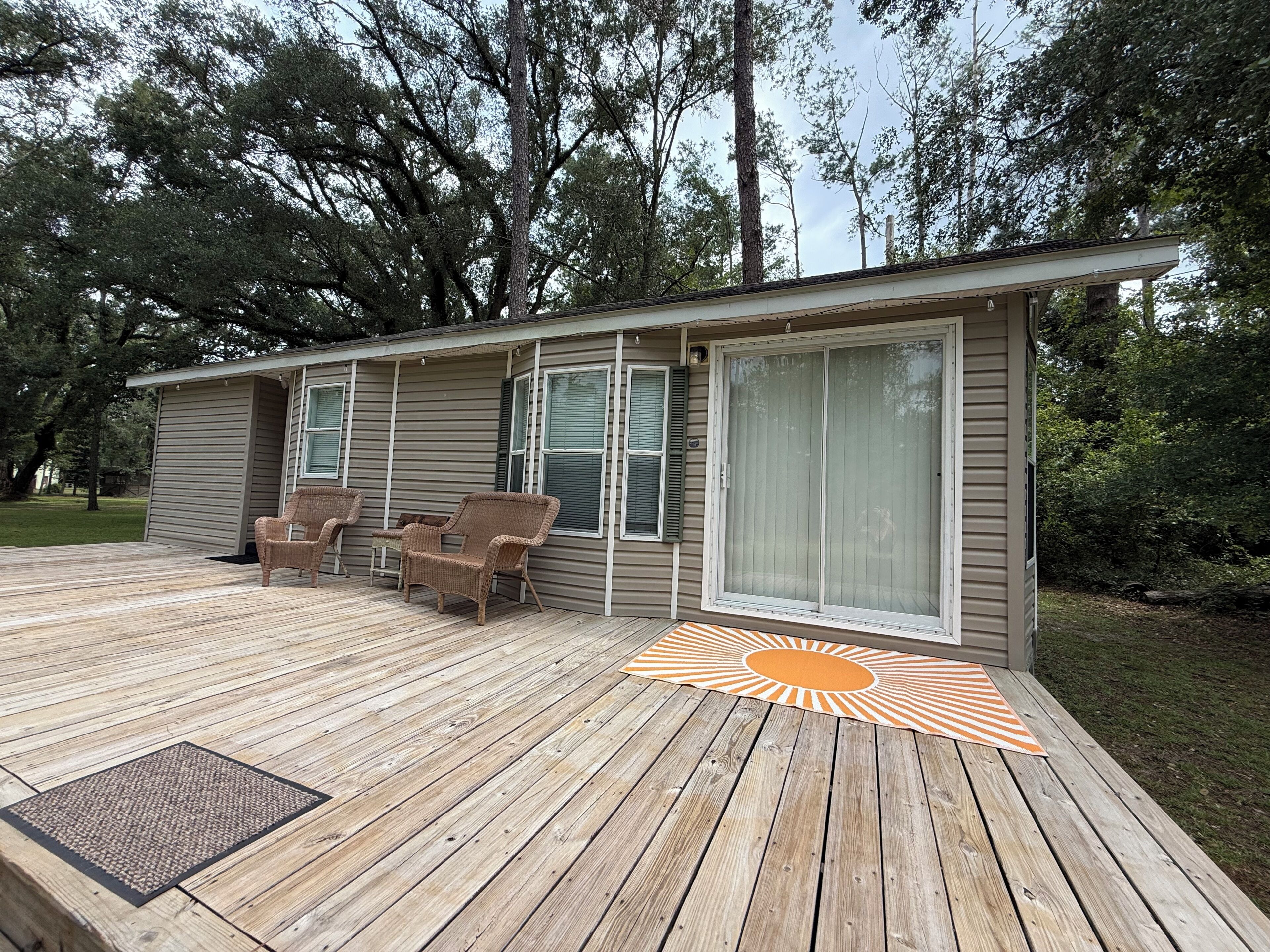 A wooden deck with outdoor furniture and a sun-shaped mat.