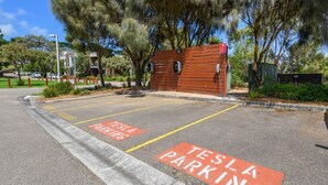 A Tesla charging station with a wooden fence and trees in the background. - Potters Hill Haven in San Remo (San Remo)