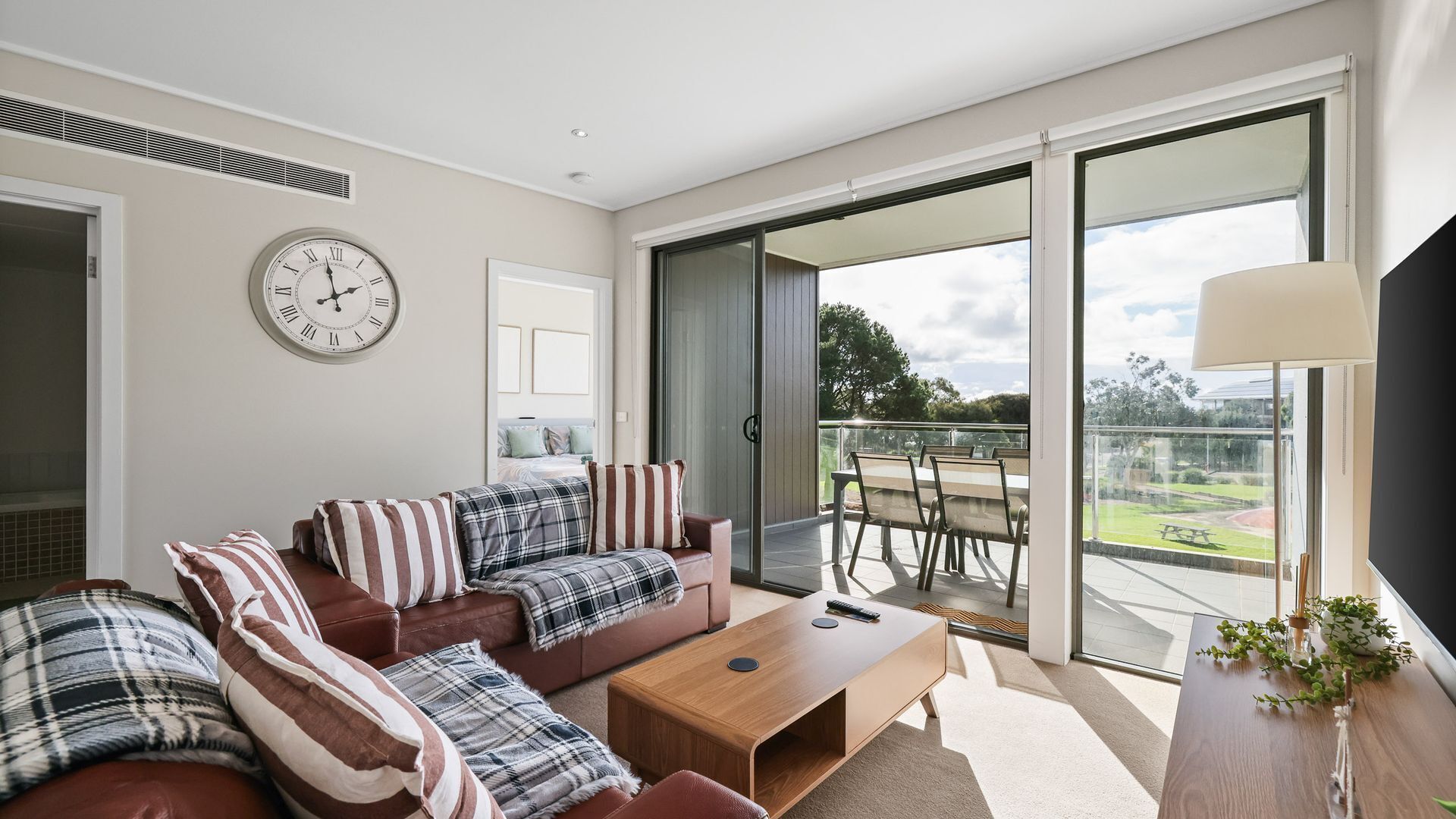 A modern living room with a sofa, coffee table, and a large window with a view of the outdoors.