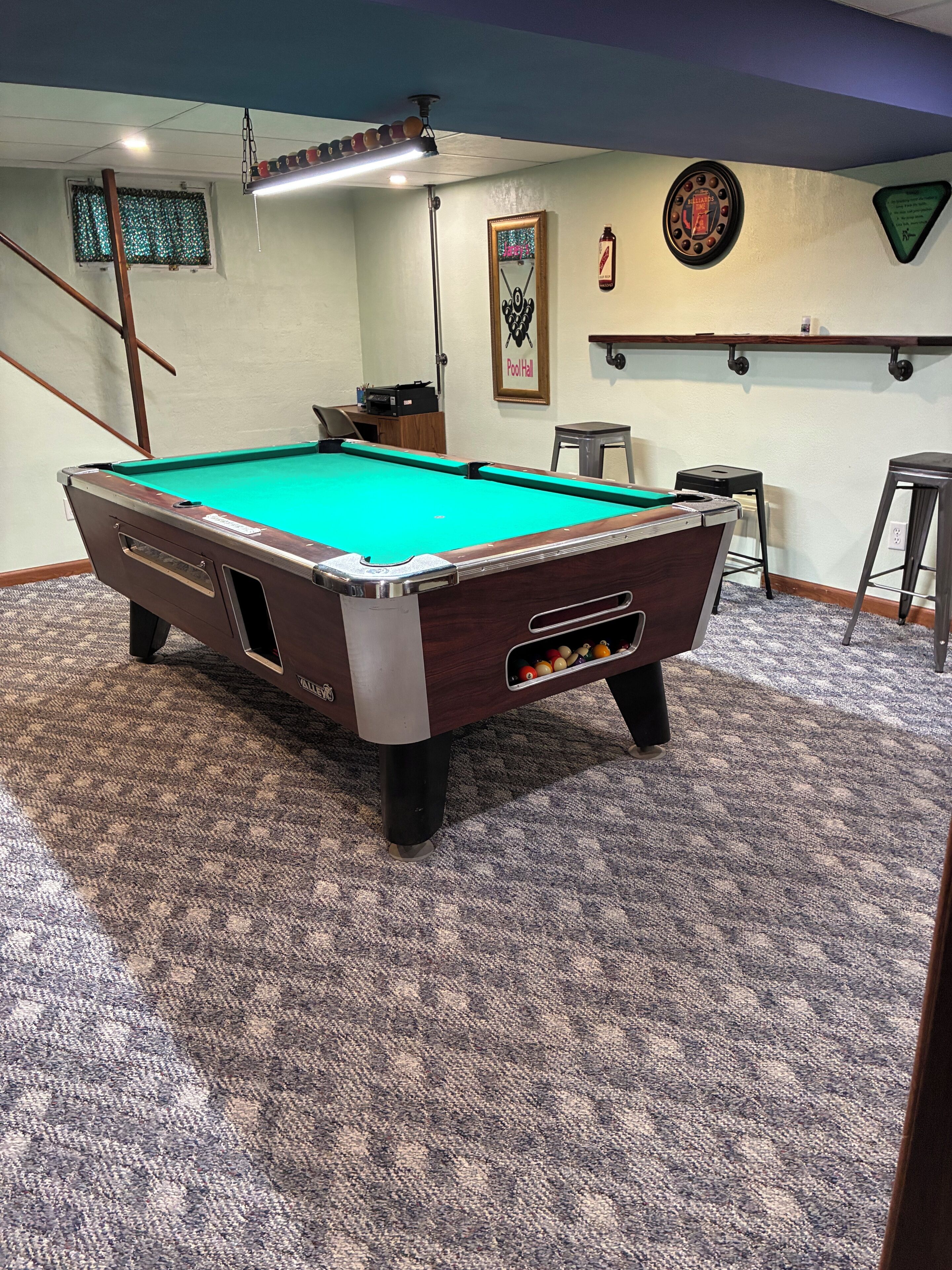 Une table de billard recouverte d’un drap vert, une queue de billard et un jeu de billes.