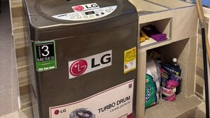 Een Turbo Drum wasmachine met 3 maanden garantie, geplaatst in een badkamer met betegelde wanden en een wastafel.