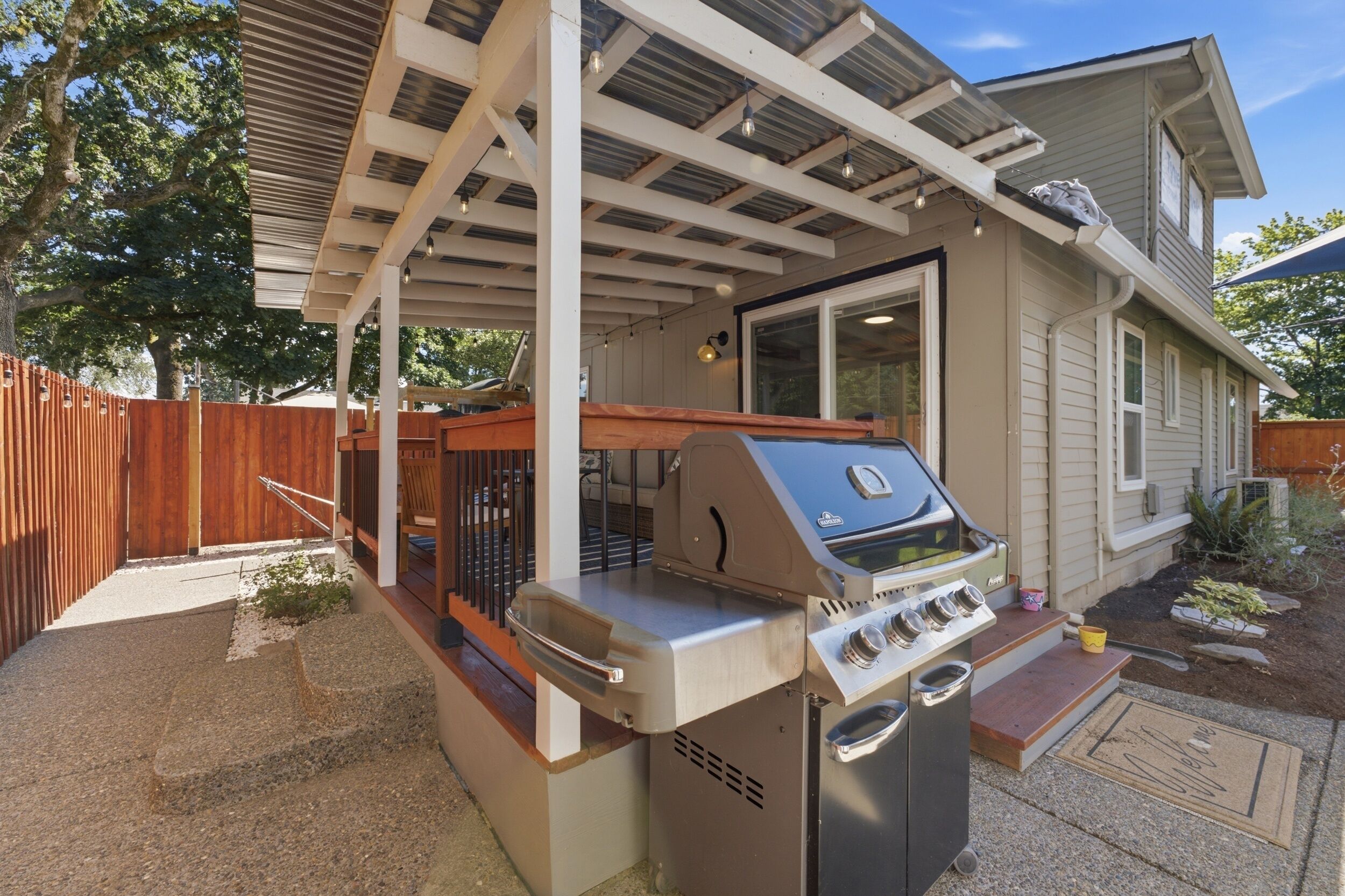 A residential property with a covered patio, a barbecue grill, and a wooden fence.