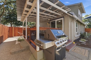 A residential property with a covered patio, a barbecue grill, and a wooden fence.