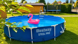 A round above-ground pool with a pink flamingo float, surrounded by a blue pool frame, and a ladder attached to the side. - Holiday Homes for 5 People Near the sea (Kamien Pomorski)