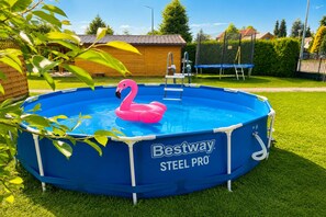 Ein runder Aufstellpool mit einem rosa Flamingo-Schwimmtier, umgeben von einem blauen Poolrahmen und einer an der Seite befestigten Leiter.
