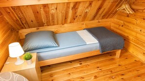 A small wooden cabin with a single bed, a bedside table with a lamp, and a small plant. - Holiday Homes for 5 People Near the sea (Kamien Pomorski)