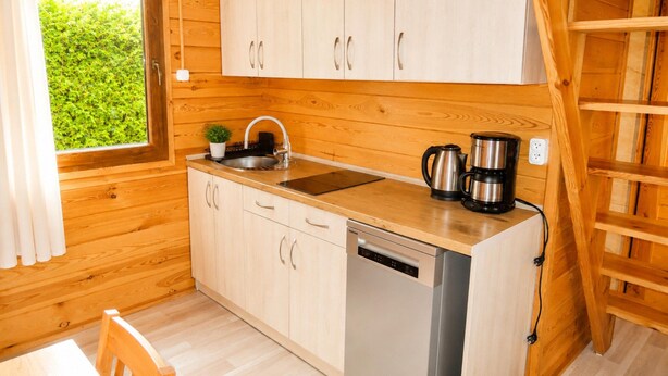 A compact kitchen with wooden cabinets, a sink, a coffee maker, and a dishwasher. - Holiday Homes for 5 People Near the sea (Kamien Pomorski)
