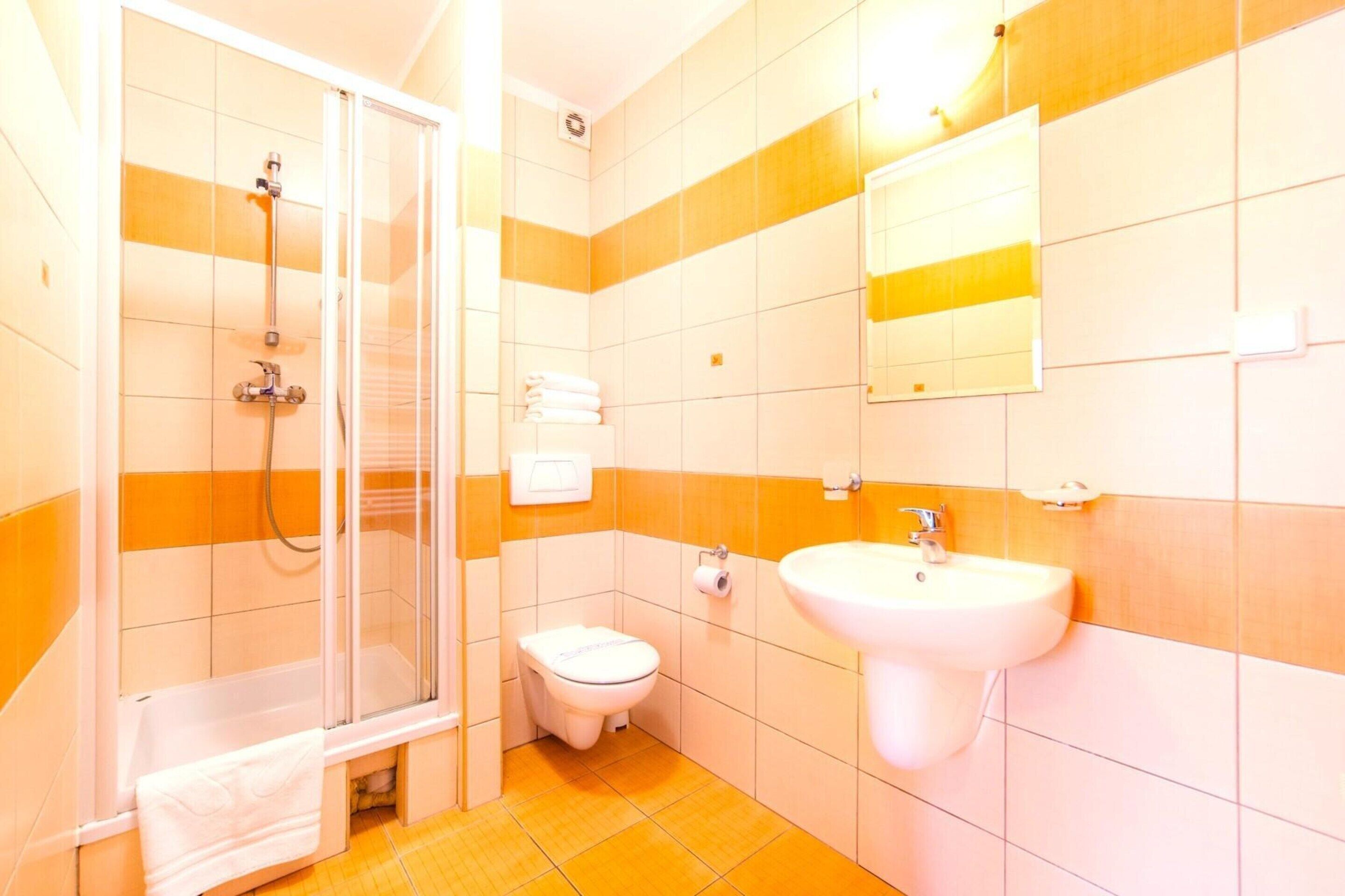 Een badkamer met douche, toilet, wastafel en spiegel.