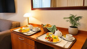 A hotel room with a dining table set for breakfast, a television, a lamp, and a potted plant. - Studio for 2 People, Dziwnowek (Dziwnów)