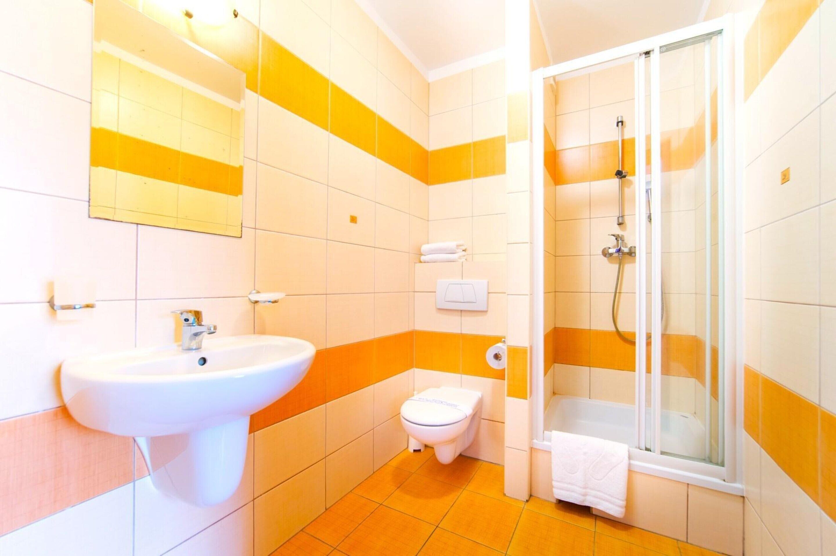 Et badeværelse med vask, toilet og brusebad.