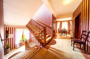 Una escalera conduce a un comedor con papel tapiz a rayas, una mesa con sillas y una planta en maceta.