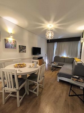 A modern living room with a dining table, sofa, and TV. - Aromas do Vouga Apartment - Termas São Pedro do SUL (São Pedro do Sul)