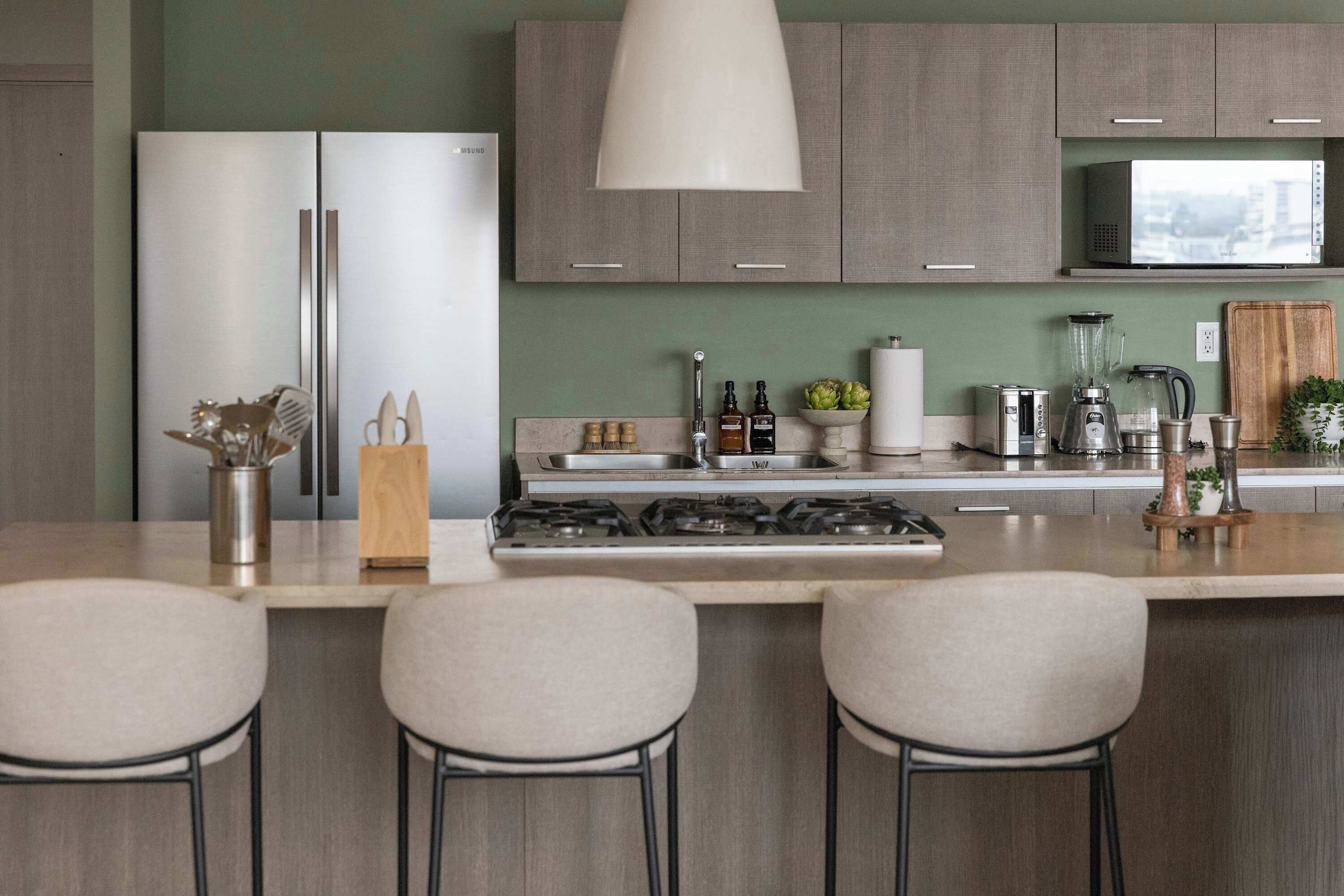 Een moderne keuken met een centraal eiland, barkrukken, een fornuis, een magnetron en een spoelbak.