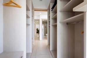 A narrow hallway with wooden shelving units on either side, leading to a bathroom with a toilet and a shower area. - Casa Azul Sky Residence | Above Polanco |Sleeps 10 (Mexico City)