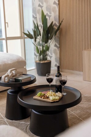 A modern living room with a round black coffee table, two black stools, a potted plant, a sofa, and a wine bottle. - Casa Azul Sky Residence | Above Polanco |Sleeps 10 (Mexico City)