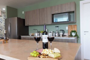 A kitchen counter with a bottle of wine, two glasses, and a selection of cheeses, fruits, and nuts. - Casa Azul Sky Residence | Above Polanco |Sleeps 10 (Mexico City)