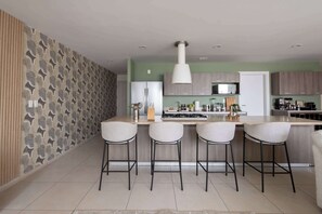 A modern kitchen with a central island, bar stools, and a patterned wallpaper. - Casa Azul Sky Residence | Above Polanco |Sleeps 10 (Mexico City)