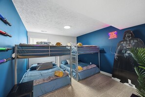 A bunk bed room with a Star Wars themed wall decoration and a neon sign.