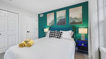 A hotel room with a bed, two bedside tables, a nightstand, a lamp, and artwork on the wall.