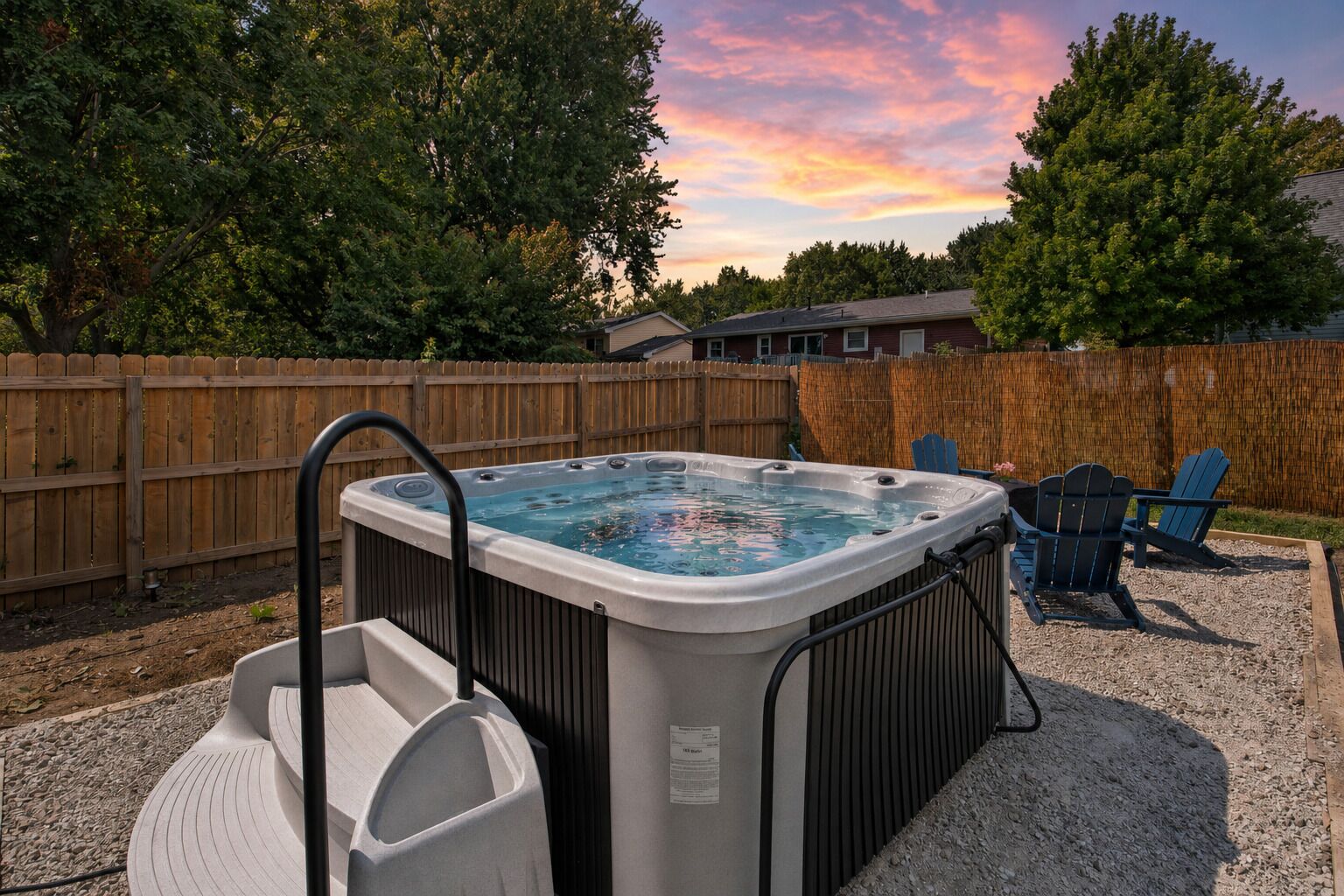 Ein Whirlpool in einem Garten mit Holzzaun, einem Stuhl und einem Kiesbereich.