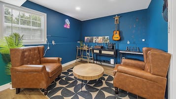 A room with blue walls, a guitar, a keyboard, and two leather armchairs.