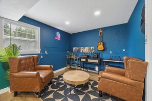 A room with blue walls, a guitar, a keyboard, and two leather armchairs.