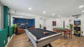 Ein Billardtisch in einem Raum mit blauer Wand, einer Gitarre und einem Spieltisch.