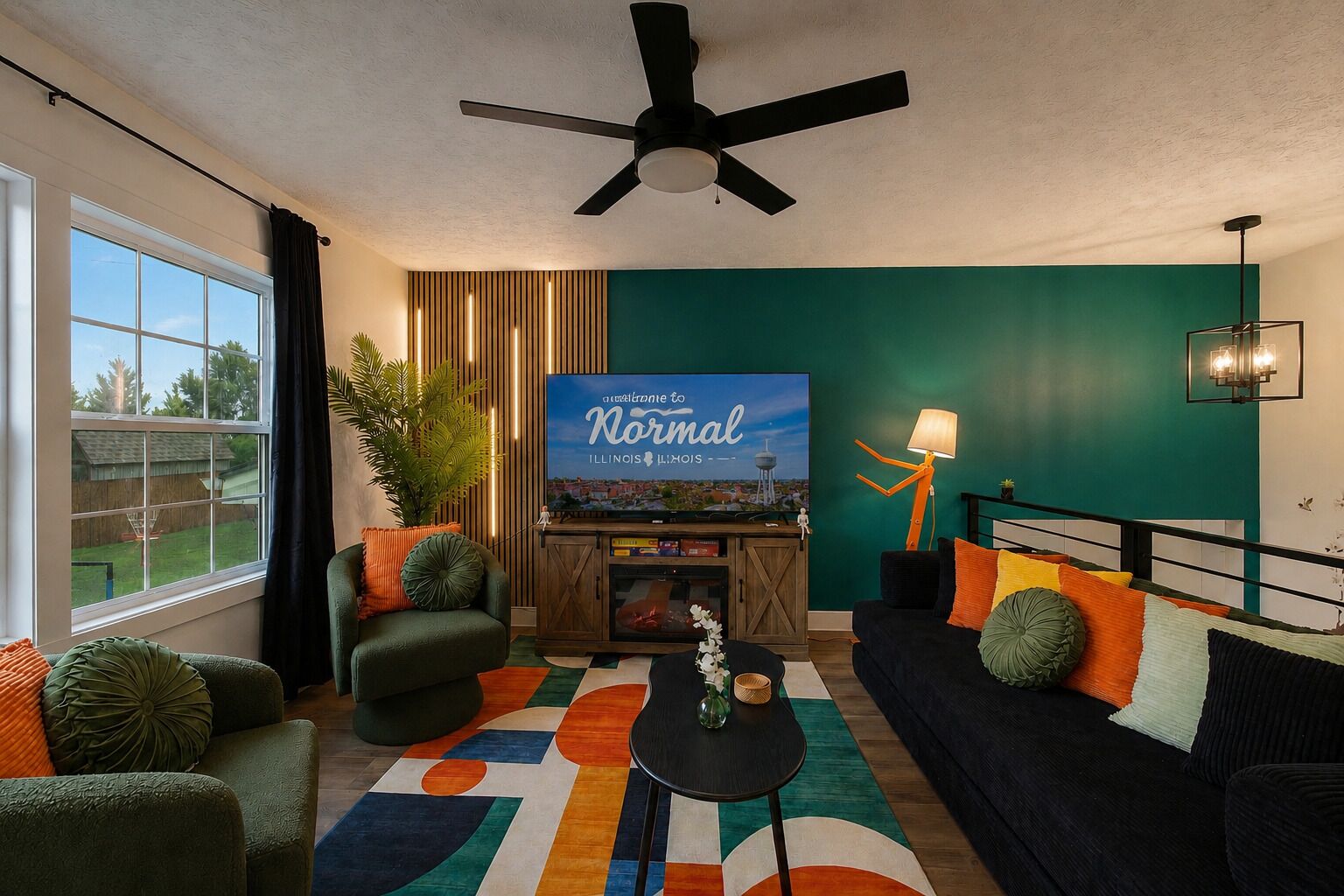 A living room with a ceiling fan, a TV mounted on a wooden cabinet, a sofa, a coffee table, and a colorful rug.