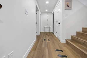 A hallway with wooden flooring, white walls, and a staircase on the right.