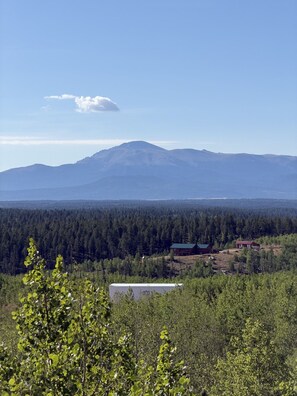 A mountainous landscape with a forested area and a small building in the foreground. - Experience Colorado’s golden hour from the comfort of your own luxury glass cabin. (Lake George)