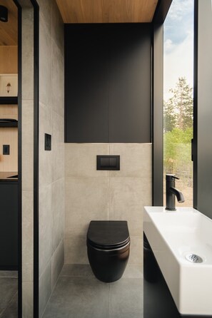 A modern bathroom with a toilet, sink, and window. - Experience Colorado’s golden hour from the comfort of your own luxury glass cabin. (Lake George)