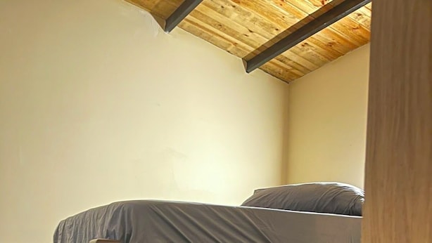 Een stapelbed met een houten frame en grijze beddengoed.