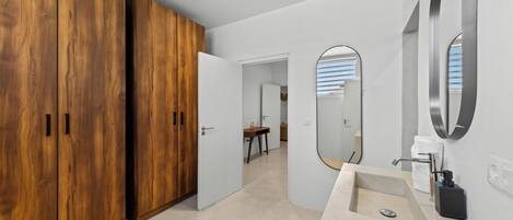 Un baño moderno con un espejo grande, un lavamanos y una zona de ducha.