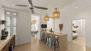 A modern kitchen with a central island, bar stools, and a ceiling fan. - Kas Leon (Willemstad)