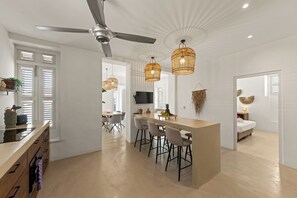 A modern kitchen with a central island, bar stools, and a ceiling fan.