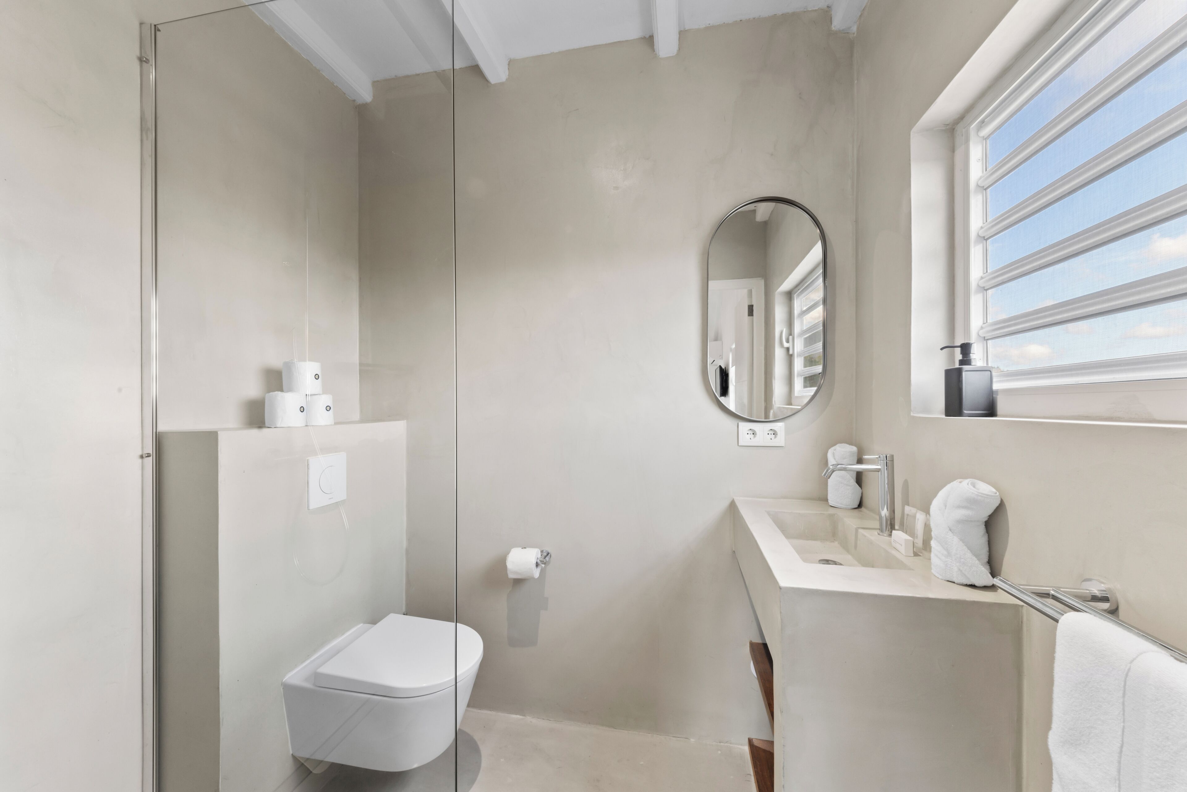 A modern bathroom with a toilet, sink, mirror, and towel rack.