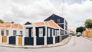 A residential street with houses featuring white and dark blue exteriors, orange tiled roofs, and white shutters. - Kas Leon (Willemstad)