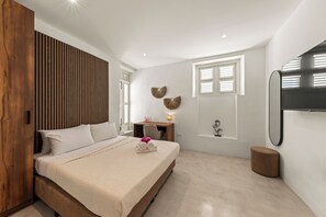 A modern bedroom with a bed, bedside table, lamp, and a wall-mounted TV.