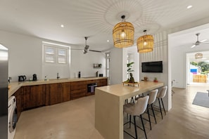A modern kitchen with a central island, wooden cabinets, a built-in oven, and a ceiling fan.