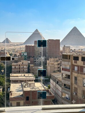 A cityscape with pyramids in the background and a street with traffic lights. - Superb 4-bedroom hotel with AC in charming Giza Governorate (Al Haram)