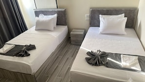 Ein Hotelzimmer mit zwei Betten, jeweils mit einem Kopfkissen und einem ordentlich gefalteten Handtuch.