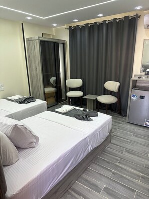 A hotel room with two beds, a small table, a chair, and a minibar.