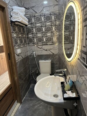 Ein Badezimmer mit marmorierter Wand, einem weißen Waschbecken mit Spiegel und einem Handtuchhalter.