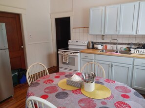 A kitchen with a dining table, white cabinets, a stove, and a sink.