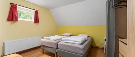 Une chambre à coucher avec un lit, un radiateur, une fenêtre avec des rideaux et une armoire.