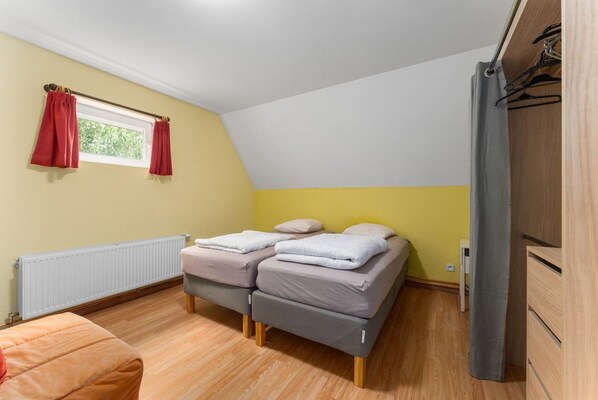 Un dormitorio con cama, radiador, ventana con cortinas y armario.