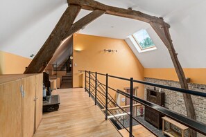A loft-style room with a wooden floor, a stone fireplace, and a skylight.