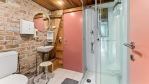 Ein Badezimmer mit einer weißen Toilette, einem Waschbecken, einem Spiegel und einer Duschkabine.